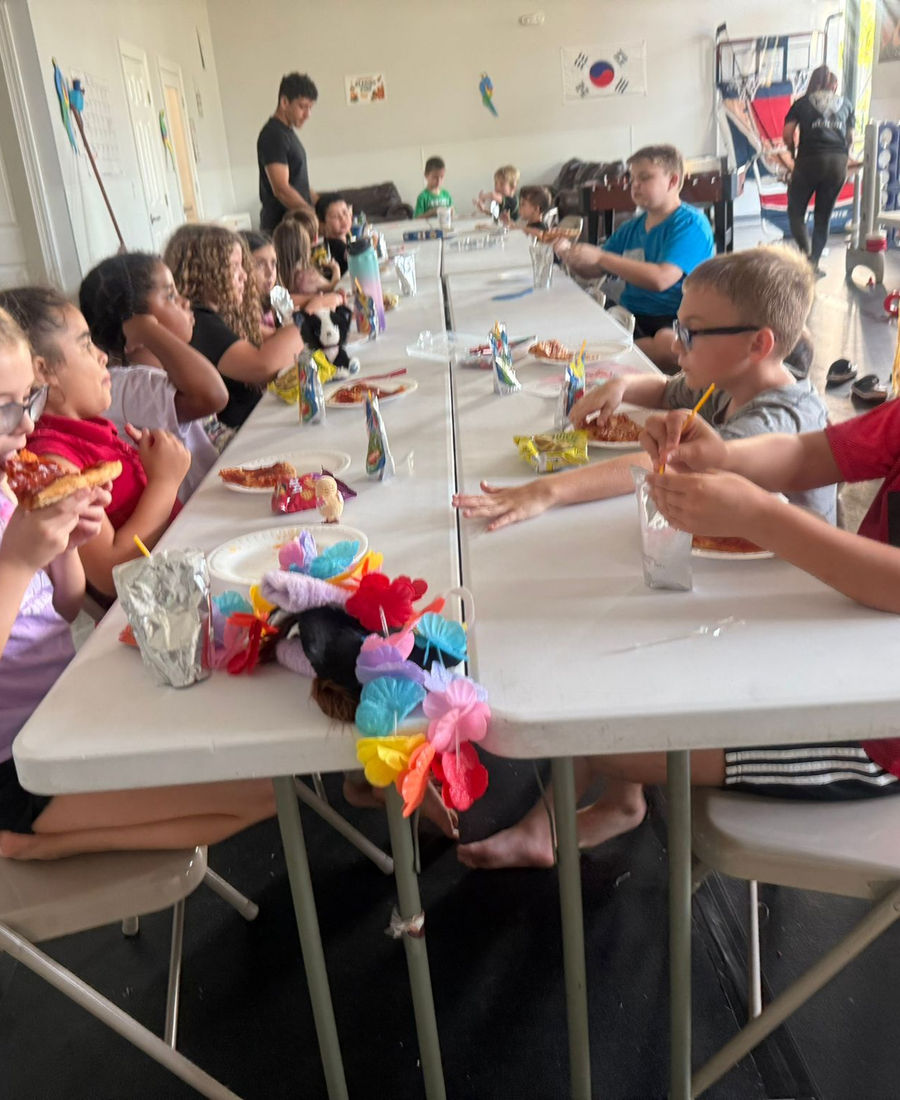 Kids enjoying pizza during Empower Martial Arts camp